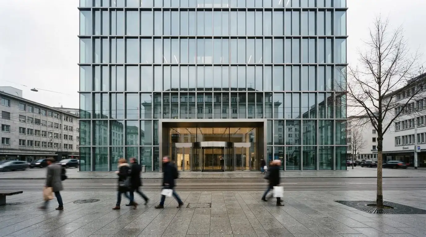 Blick auf ein Bankgebäude mit Glasfassade von der Strasse aus, Passanten gehen unscharf vorbei.